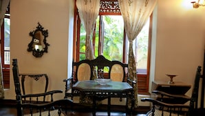 Una habitación tradicional con una mesa y sillas de madera, un espejo y una ventana con cortinas.