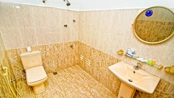 Et badeværelse med toilet, håndvask og brusebad.