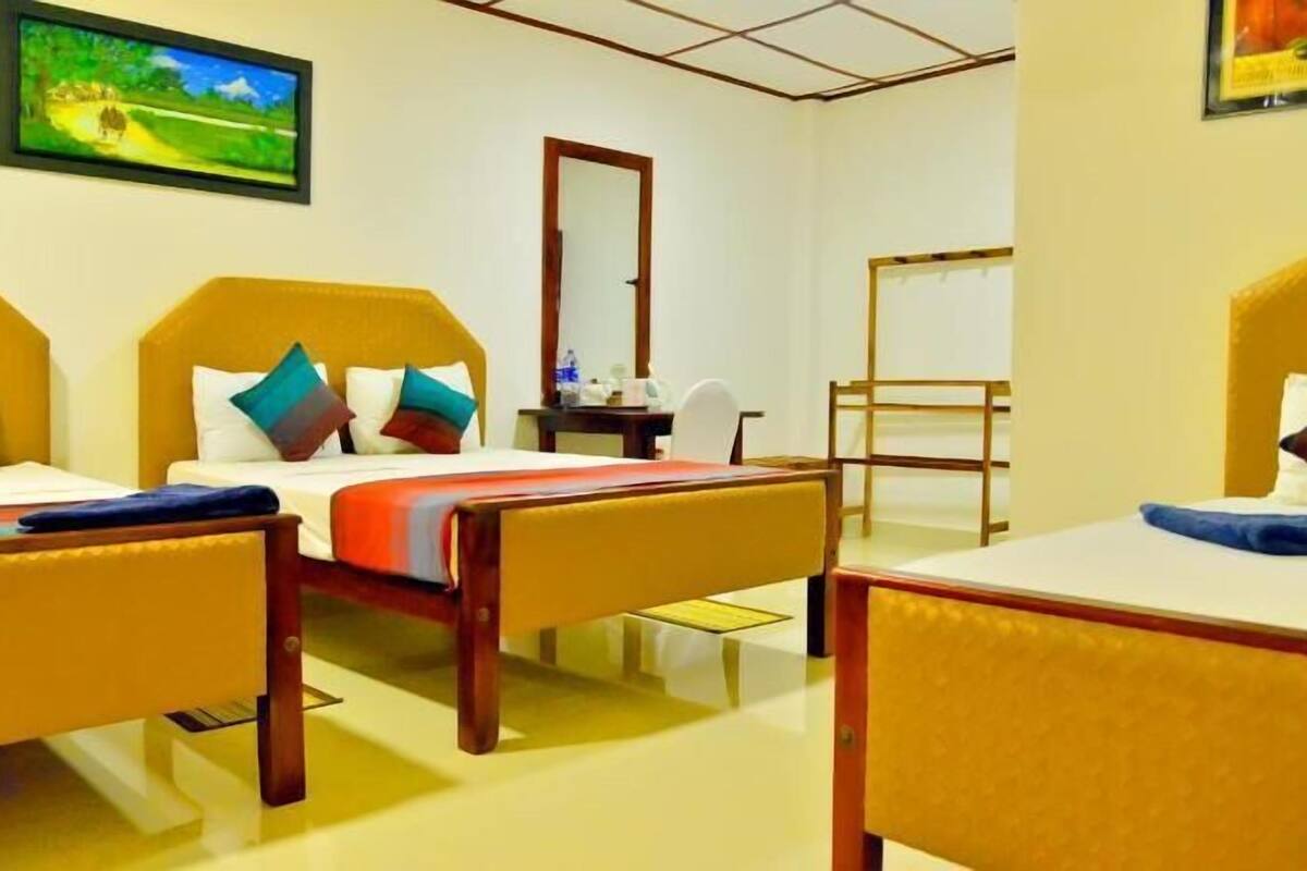 Habitación de hotel con dos camas, un escritorio, una silla, un espejo y un cuadro en la pared.