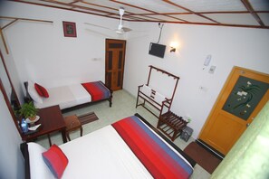 A room with two beds, a desk, a chair, a television, and a door. - Thilaka City Hotel (Anuradhapura)