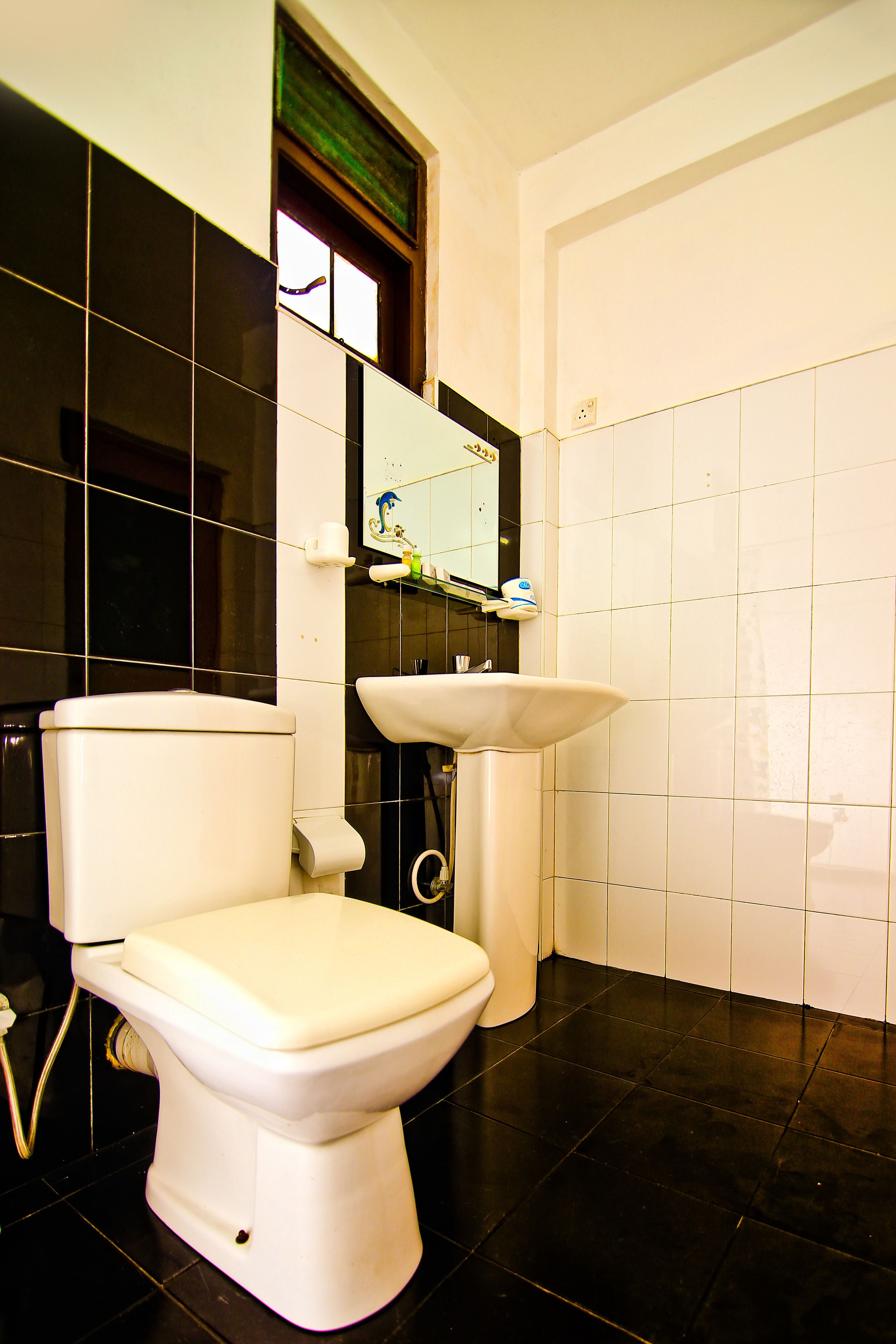 A bathroom with a toilet, sink, and mirror.