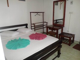 Un dormitorio con cama, un escritorio de madera, una silla, un perchero y un espejo.
