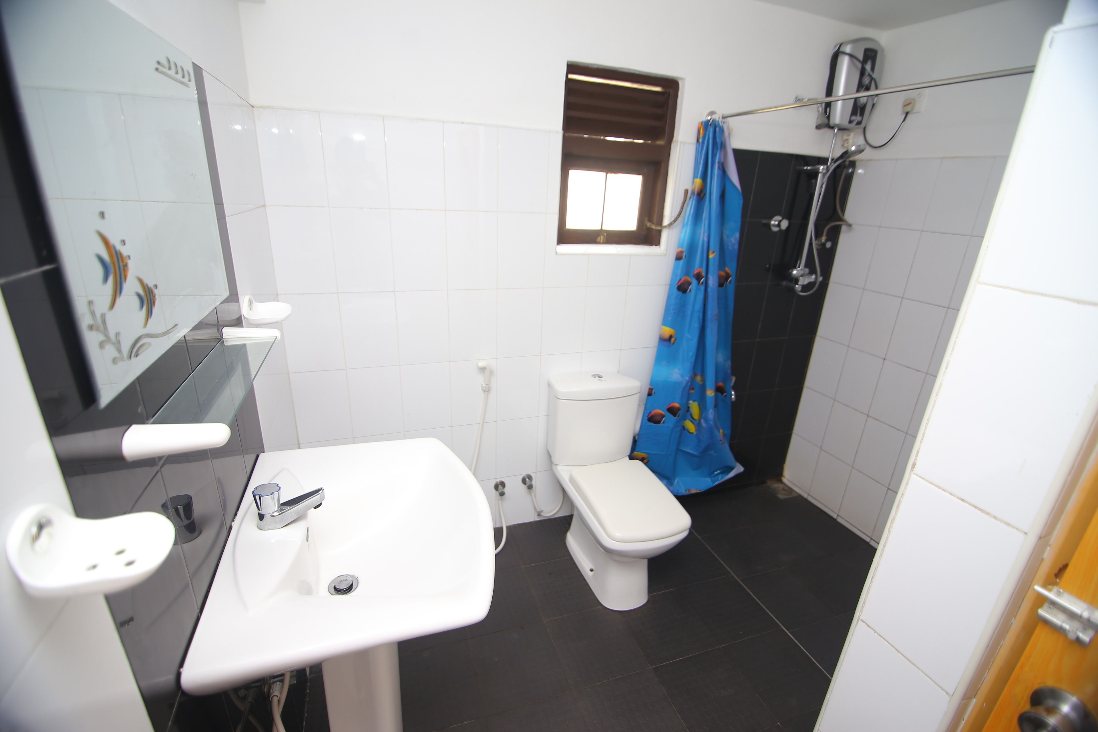 A bathroom with a white sink, a toilet, and a shower area.