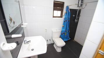 A bathroom with a white sink, a toilet, and a shower area.