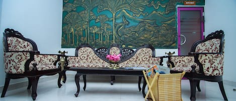 A room with a sofa set, a small table with magazines, and a large decorative painting on the wall.