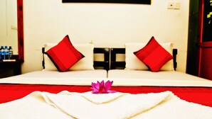 Una cama bien hecha con ropa de cama roja y blanca, una sola almohada roja y una toalla blanca en el suelo.