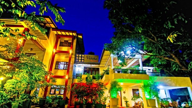 Un hotel con varios pisos, terraza exterior y una entrada bien iluminada.
