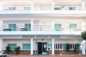 A two-story building with balconies, a sign reading 'HOSTAL SUNSET IBIZA,' and outdoor seating. - Hostal Sunset Ibiza (Sant Antoni de Portmany)