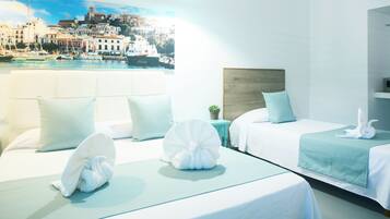 Habitación de hotel con dos camas, vista a un pueblo costero y un ventanal grande.