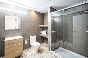 Un baño moderno con inodoro, tocador y zona de ducha.