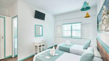 Una habitación con dos camas, un escritorio, una silla, un televisor y una ventana con persianas.