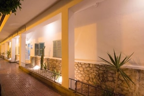 A corridor with stone walls, metal railings, and potted plants. - Hostal Sunset Ibiza (Sant Antoni de Portmany)