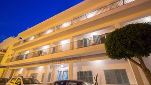 A multi-story building with balconies, a sign reading "Hostal Sunset Ibiza," and parked cars. - Hostal Sunset Ibiza (Sant Antoni de Portmany)
