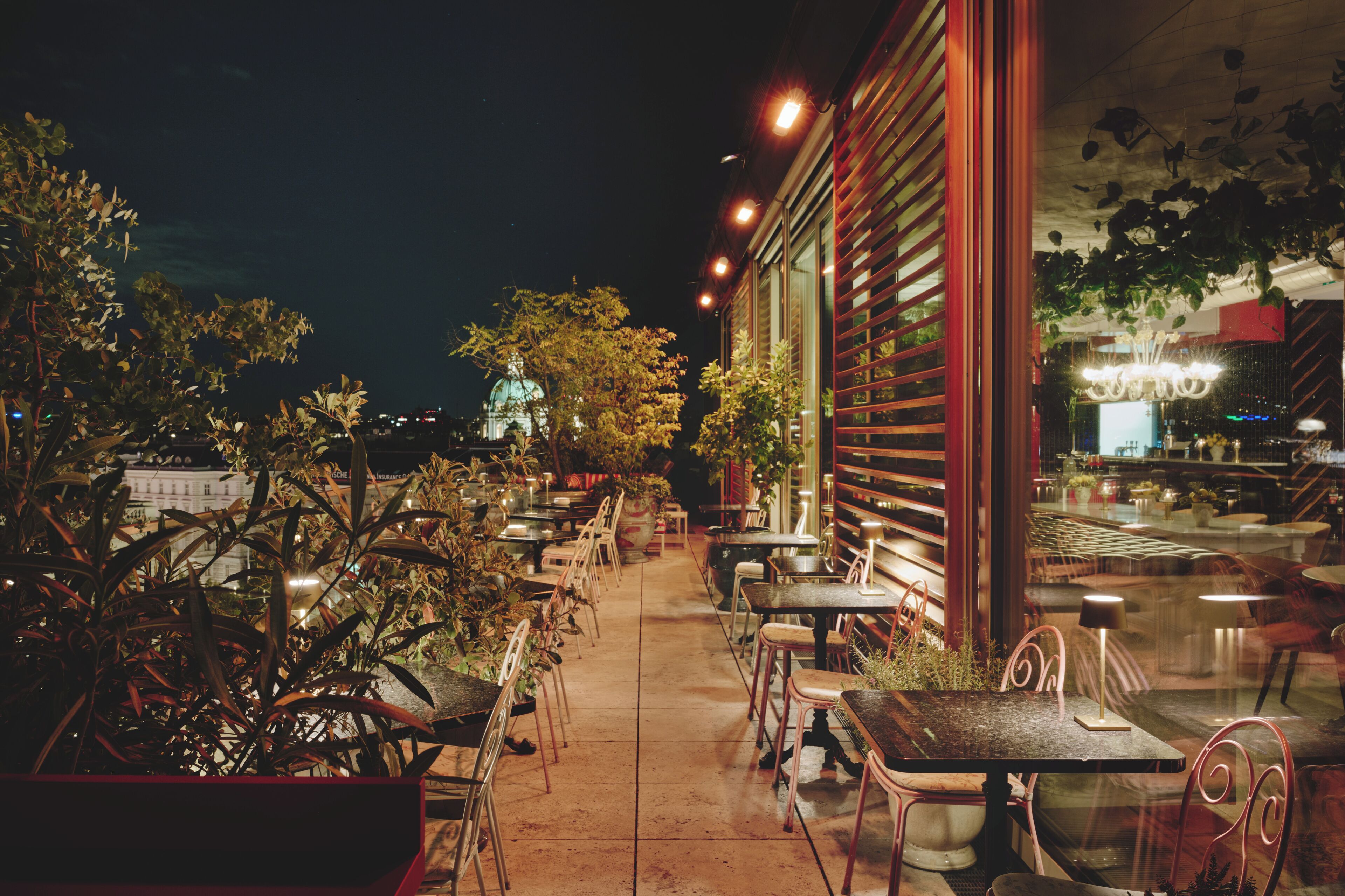 An outdoor cafe with tables and chairs, a view of a building with a dome, and a staircase leading to an upper level.