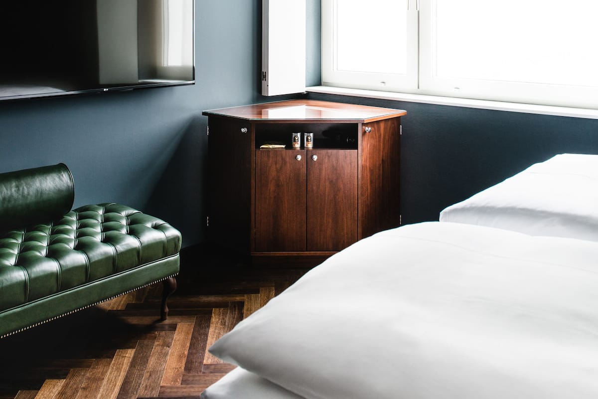 Une pièce comprenant un lit, un canapé en cuir vert, une armoire en bois et un téléviseur à écran plat fixé au mur.