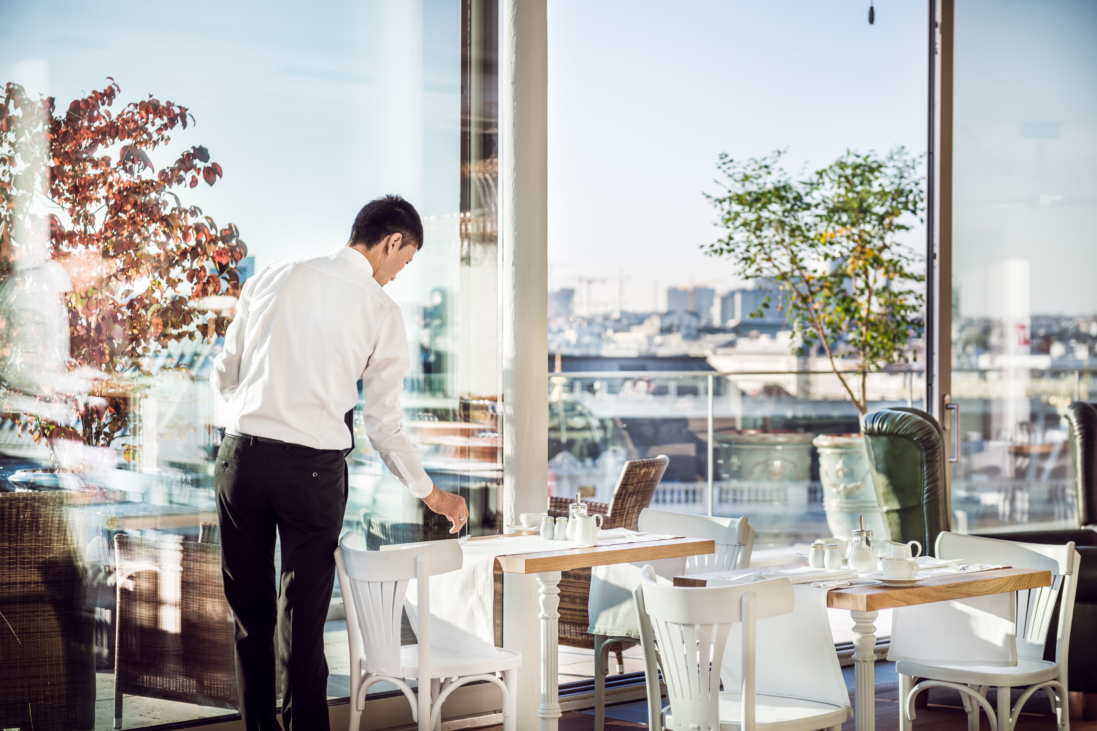 Un restaurant moderne offrant une vue imprenable sur la ville grâce à de grandes fenêtres.