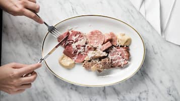Um prato com fatias de carne e queijo sobre uma superfície de mármore.