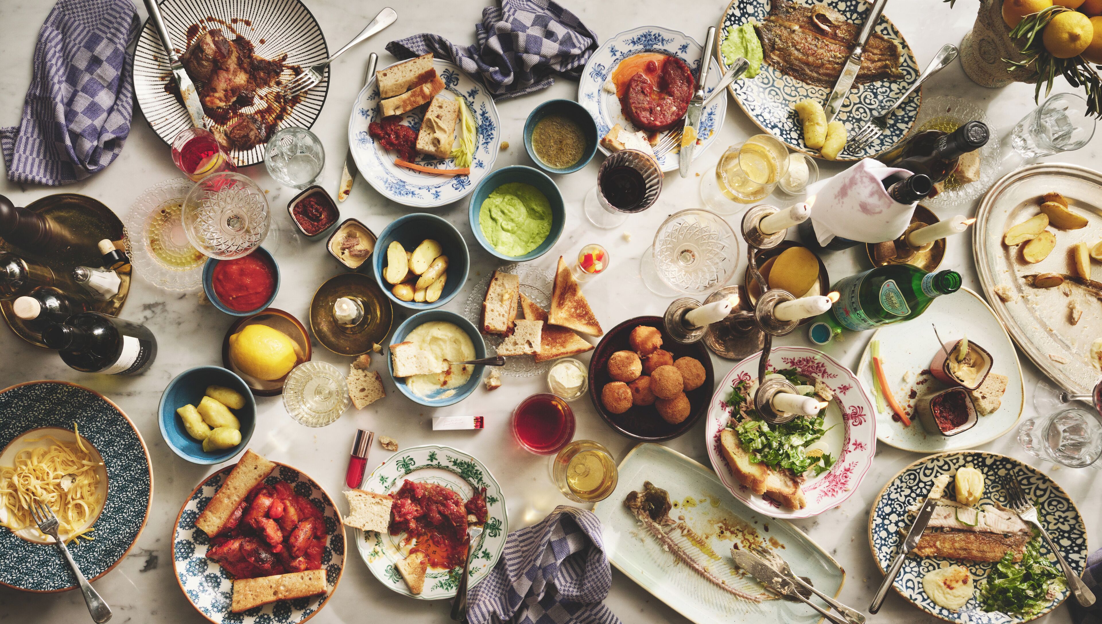 A table with various dishes, drinks, and utensils, suggesting a meal setting.