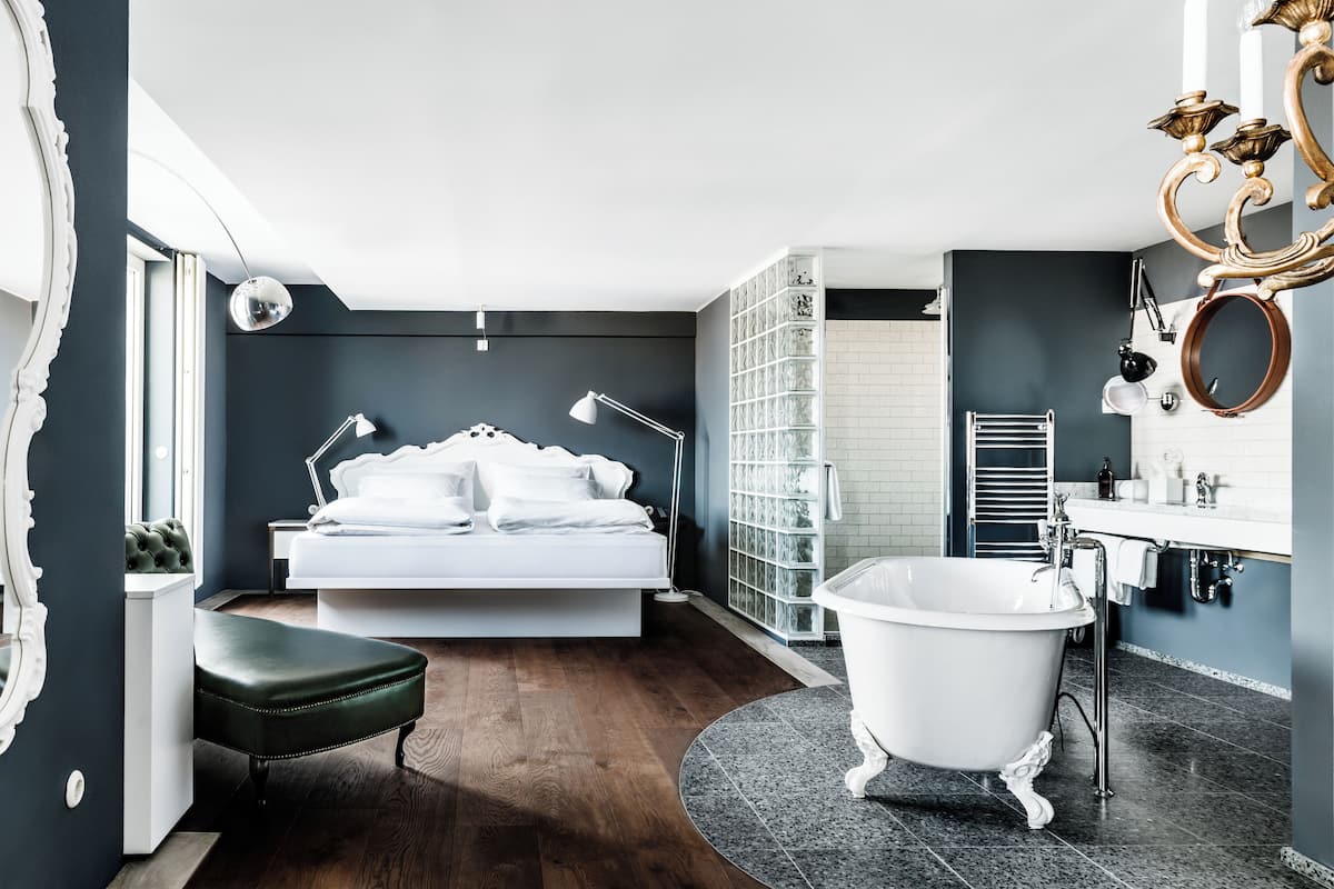 Une chambre moderne avec un grand lit, une coiffeuse avec baignoire et un dressing.
