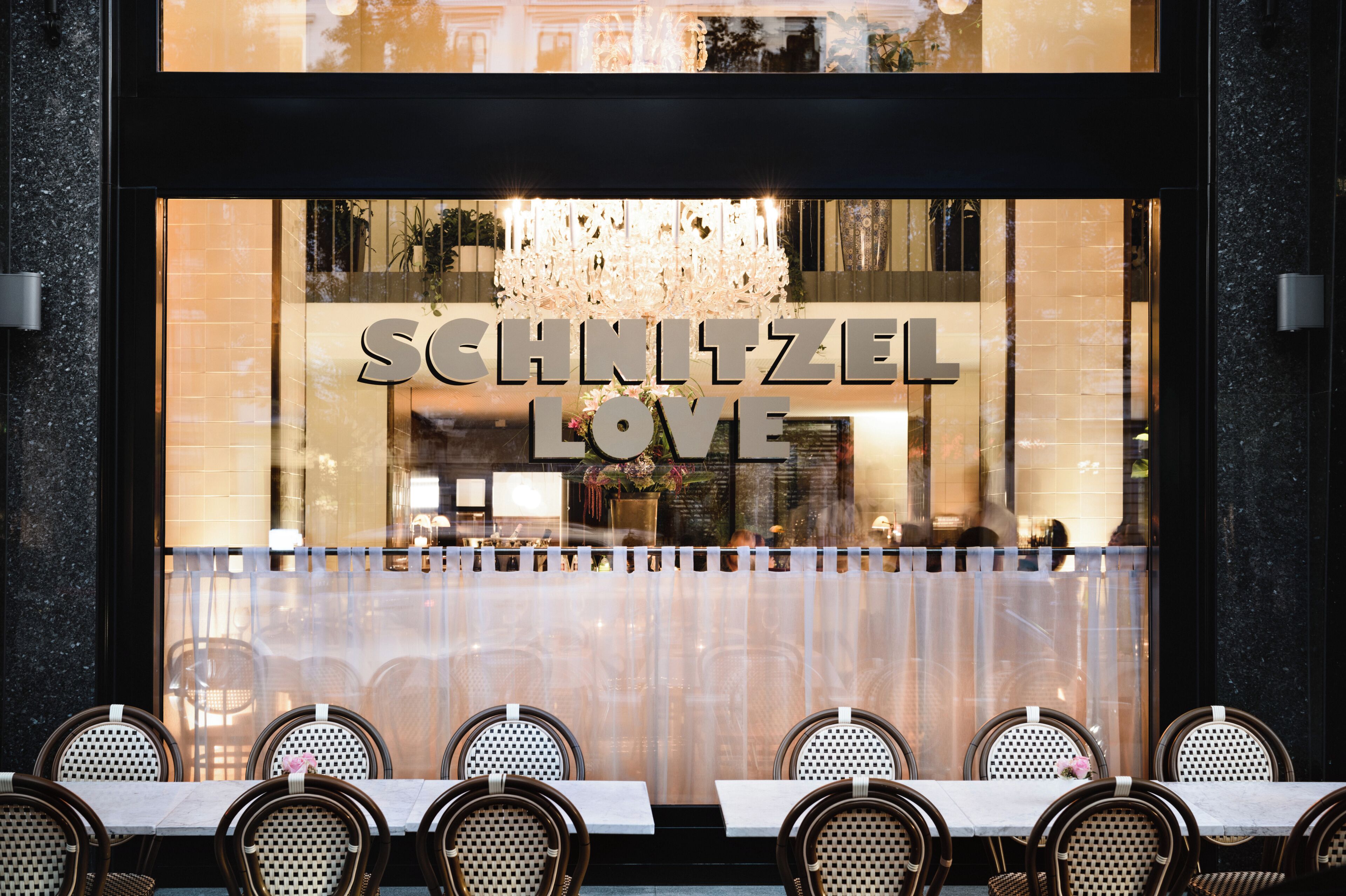 A restaurant with a sign reading 'SCHNITZEL LOVE' and a chandelier above the entrance.