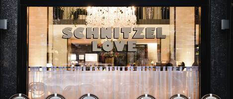A restaurant with a sign reading 'SCHNITZEL LOVE' and a chandelier above the entrance.