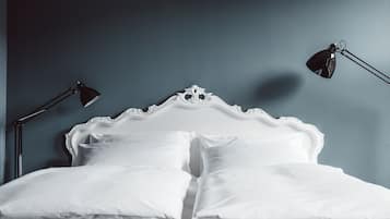 A neatly made bed with white linens, a classic headboard, and two bedside lamps.