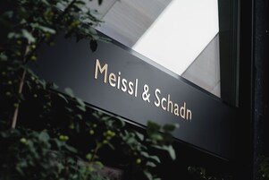 Uma placa com o nome 'Meissl & Schadn' sobre um fundo preto.