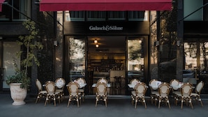 A restaurant with outdoor seating, a red awning, and a sign reading "Gulash & Sonne". - Hotel Grand Ferdinand Vienna (Vienna)