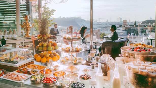 A buffet setup with various food items and a view of the cityscape. - Hotel Grand Ferdinand Vienna (Vienna)