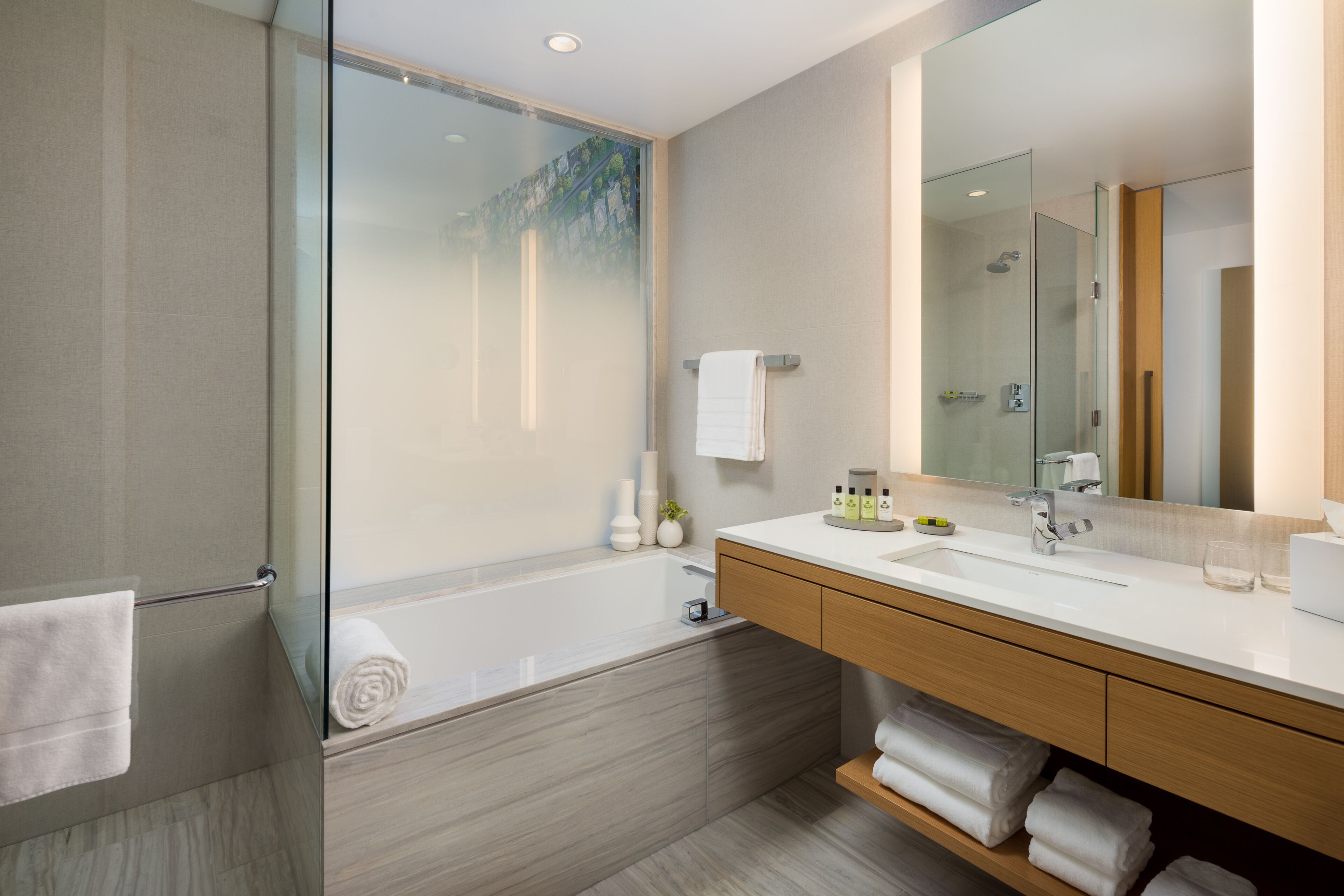 A modern bathroom with a glass-enclosed shower, a large mirror, and a wooden vanity with a white sink.