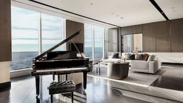 A spacious living room with a grand piano, a modern sofa, and a city view through large windows.