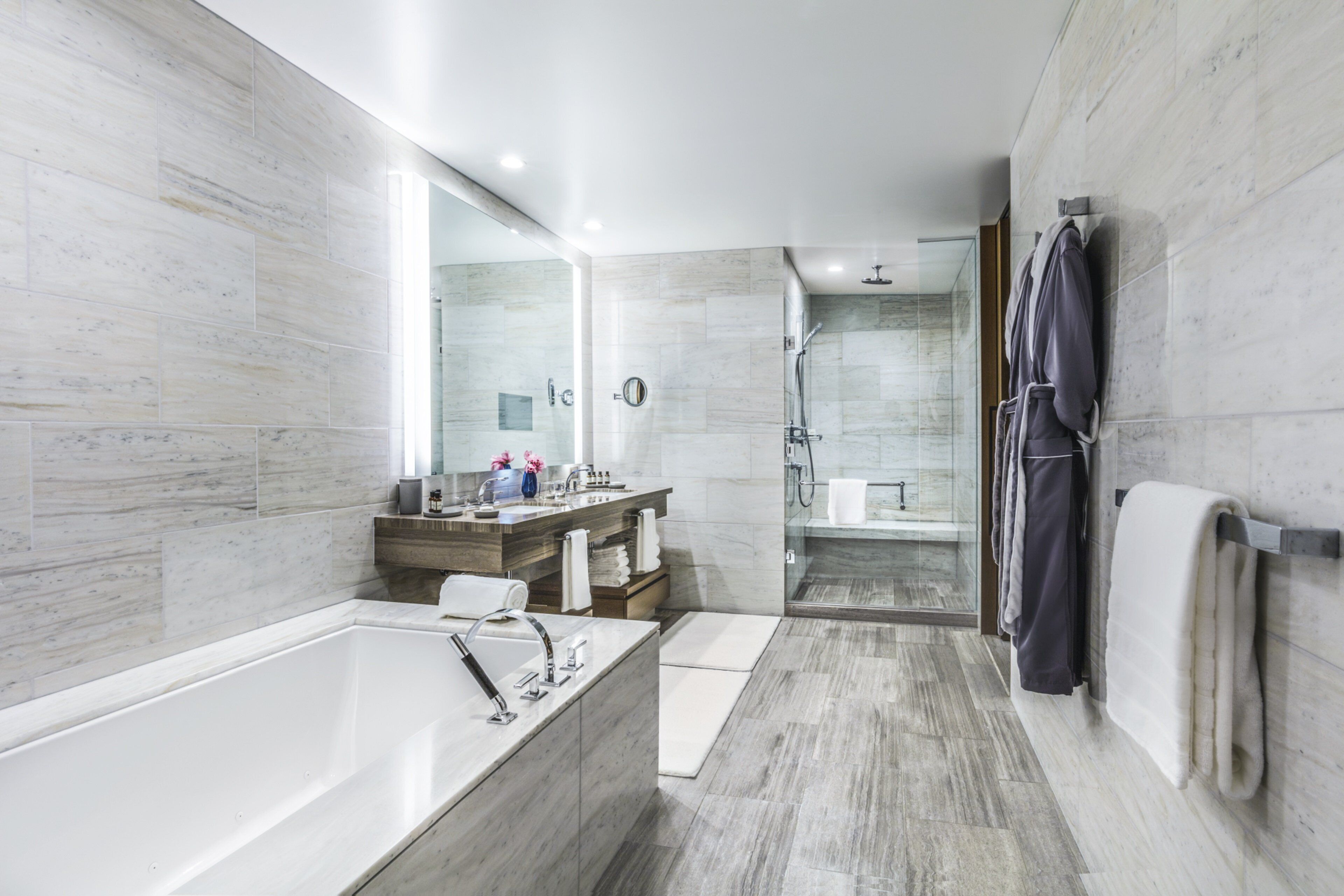 A modern bathroom with a large bathtub, a shower area, and a vanity with a mirror.