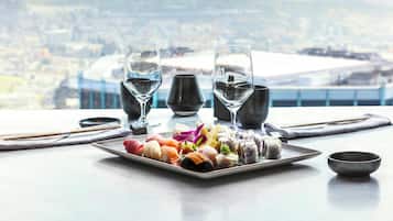 Une table avec un plateau de sushis, deux verres d’eau, des baguettes, un bol et une vue sur un stade.