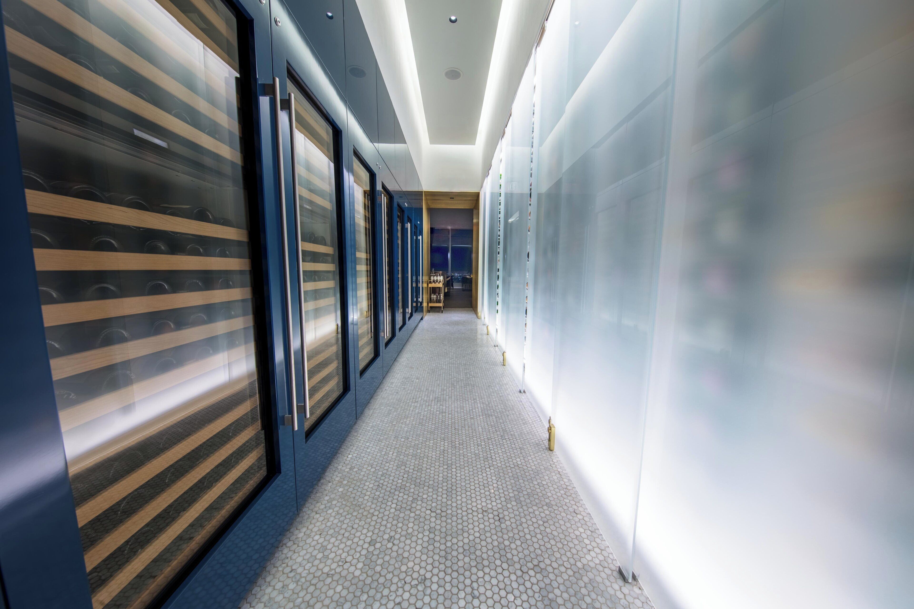 A corridor with glass doors on one side and a tiled floor.