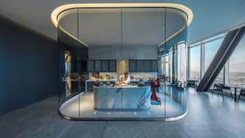A modern kitchen with a central island, glass walls, and a city view.