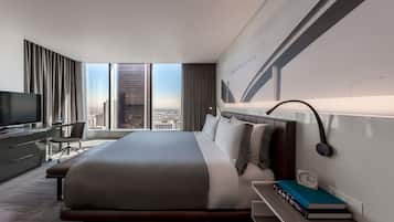 Een moderne hotelkamer met een groot bed, een bureau met een computer, een televisie en uitzicht over de stad.