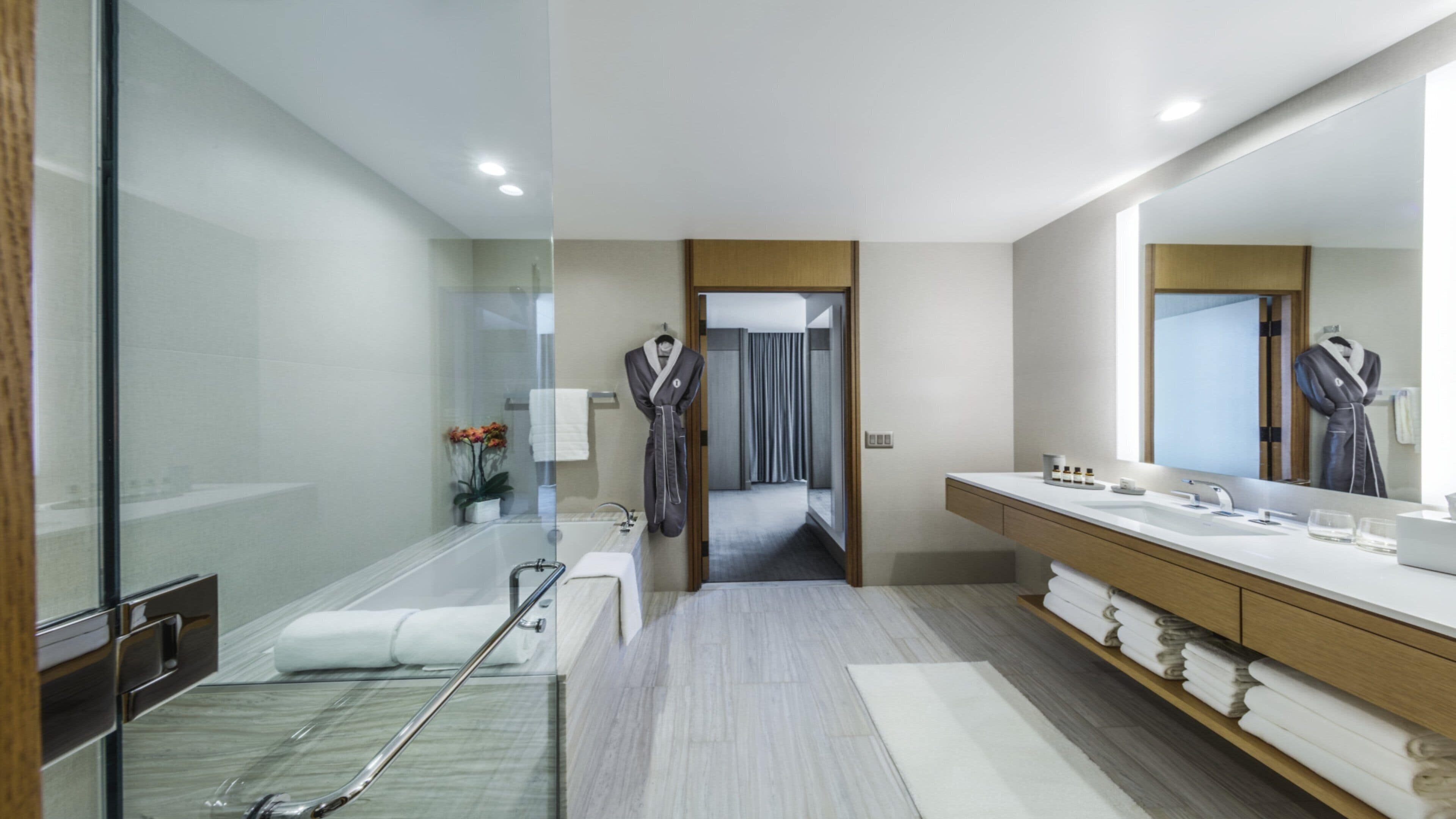 A modern bathroom with a glass shower enclosure, a bathtub, a vanity with a mirror, and a walk-in shower.