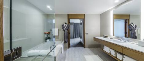 A modern bathroom with a glass shower enclosure, a bathtub, a vanity with a mirror, and a walk-in shower.
