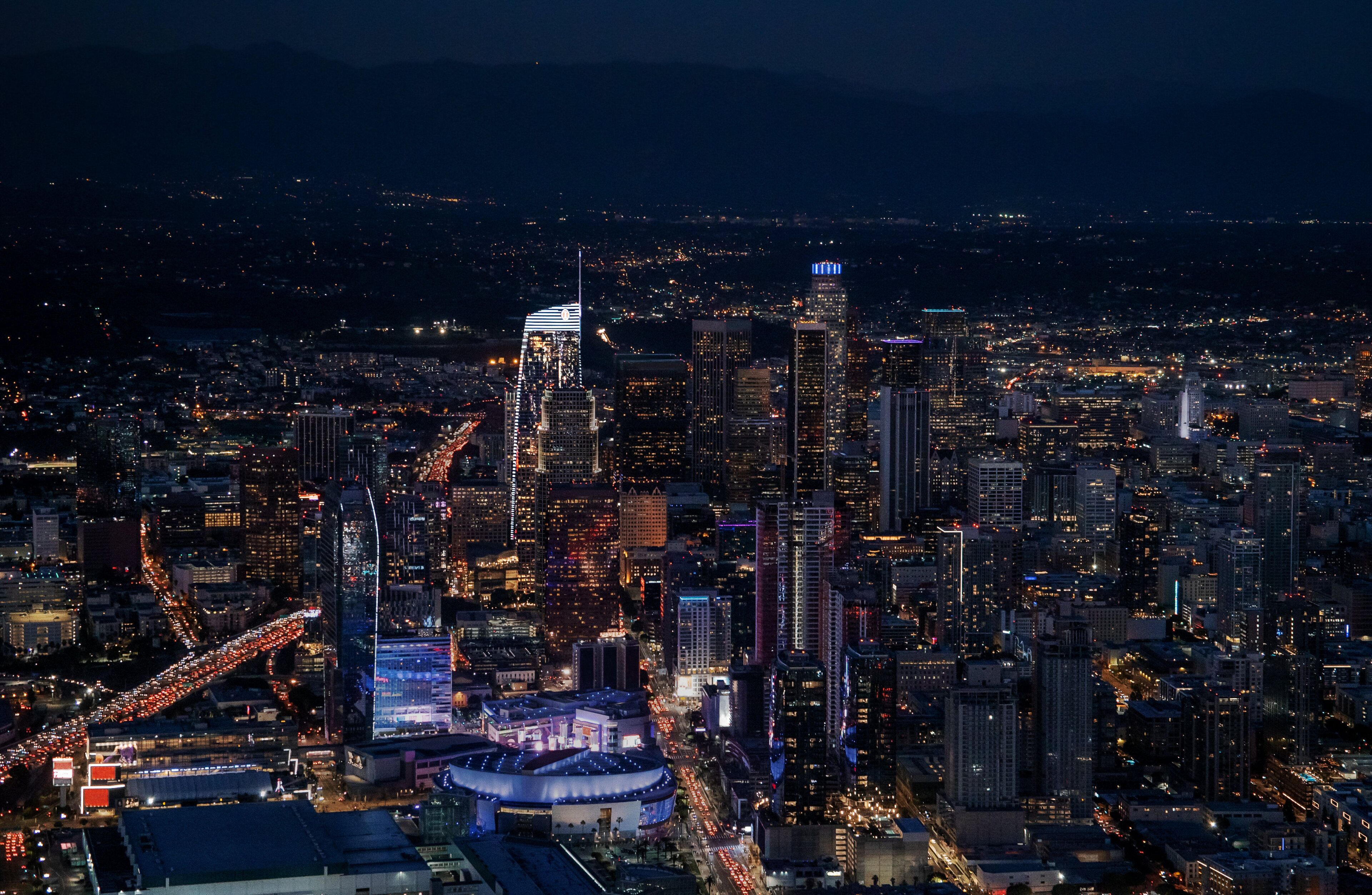 A nighttime cityscape with high-rise buildings and illuminated streets.