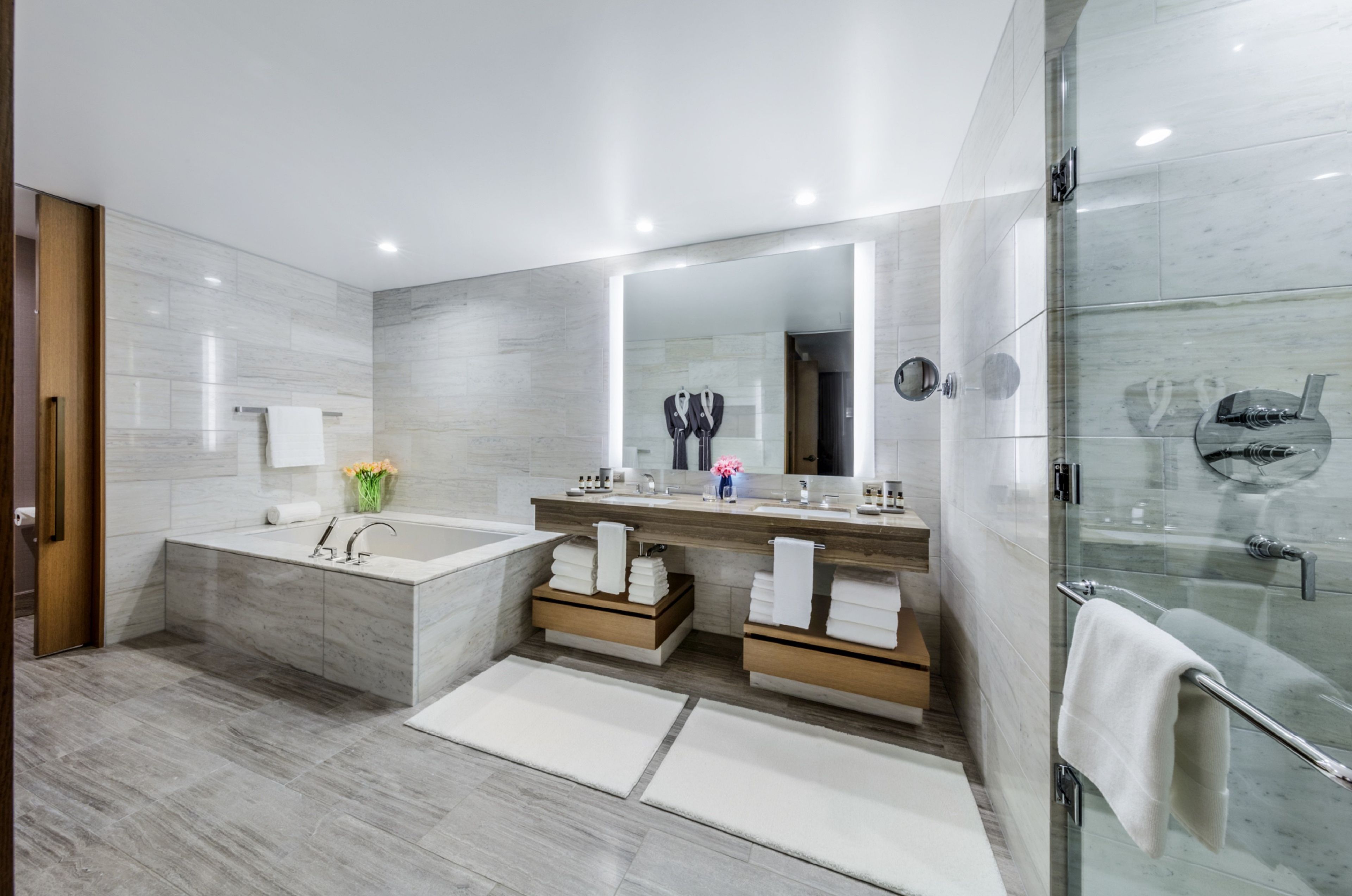 Un baño moderno con una bañera grande, cabina de ducha con mampara de vidrio y tocador con espejo.