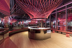 Un interior moderno con una barra circular central, iluminación roja y ventanas amplias.