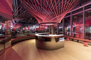 Un interno moderno con un bancone bar circolare centrale, illuminazione rossa e ampie finestre.