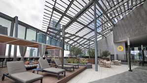 A modern outdoor lounge area with sun loungers and seating, a glass ceiling, and a view of the cityscape. - InterContinental Los Angeles Downtown by IHG (Los Angeles)