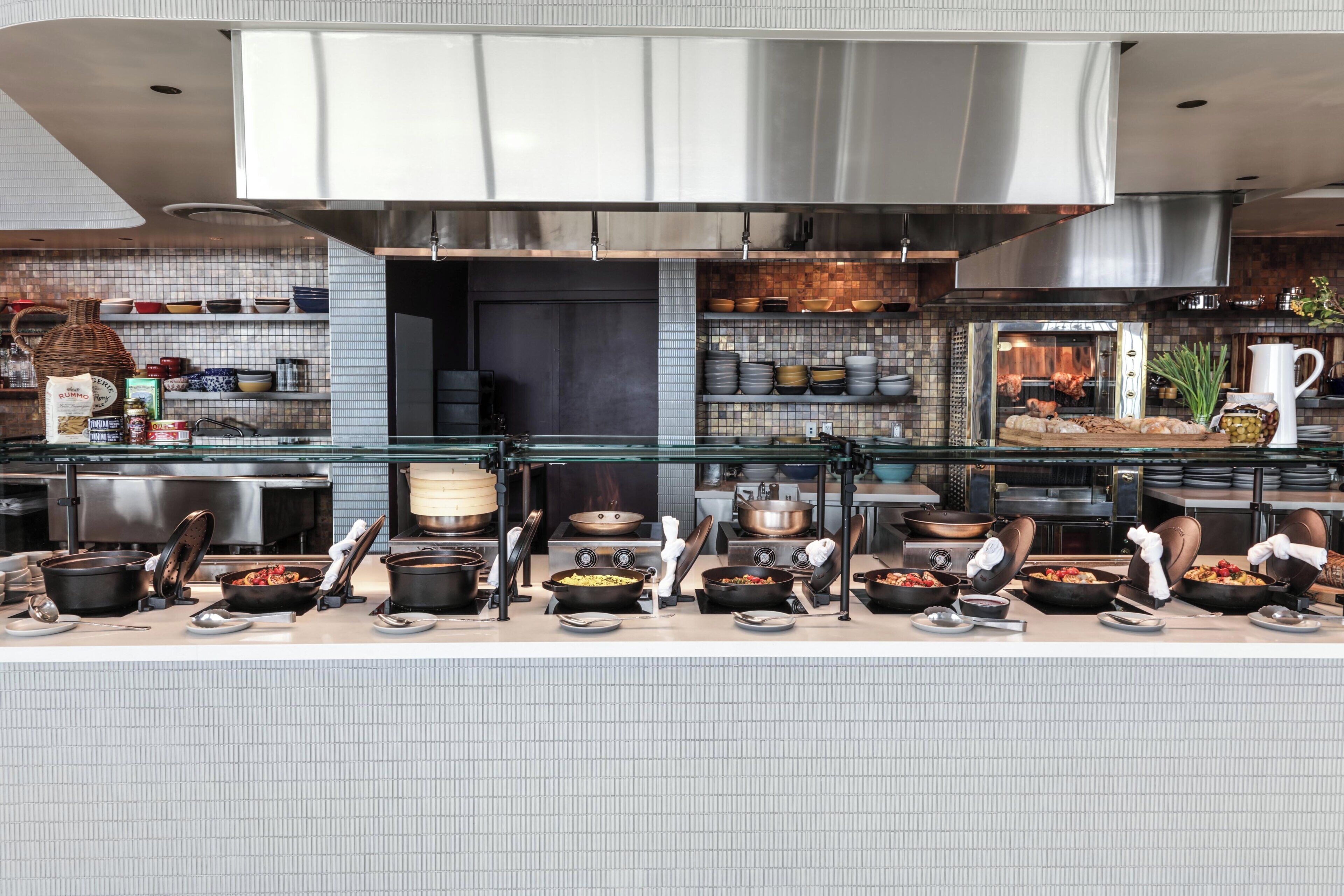 A commercial kitchen with stainless steel appliances, a variety of cookware, and a display of food items.