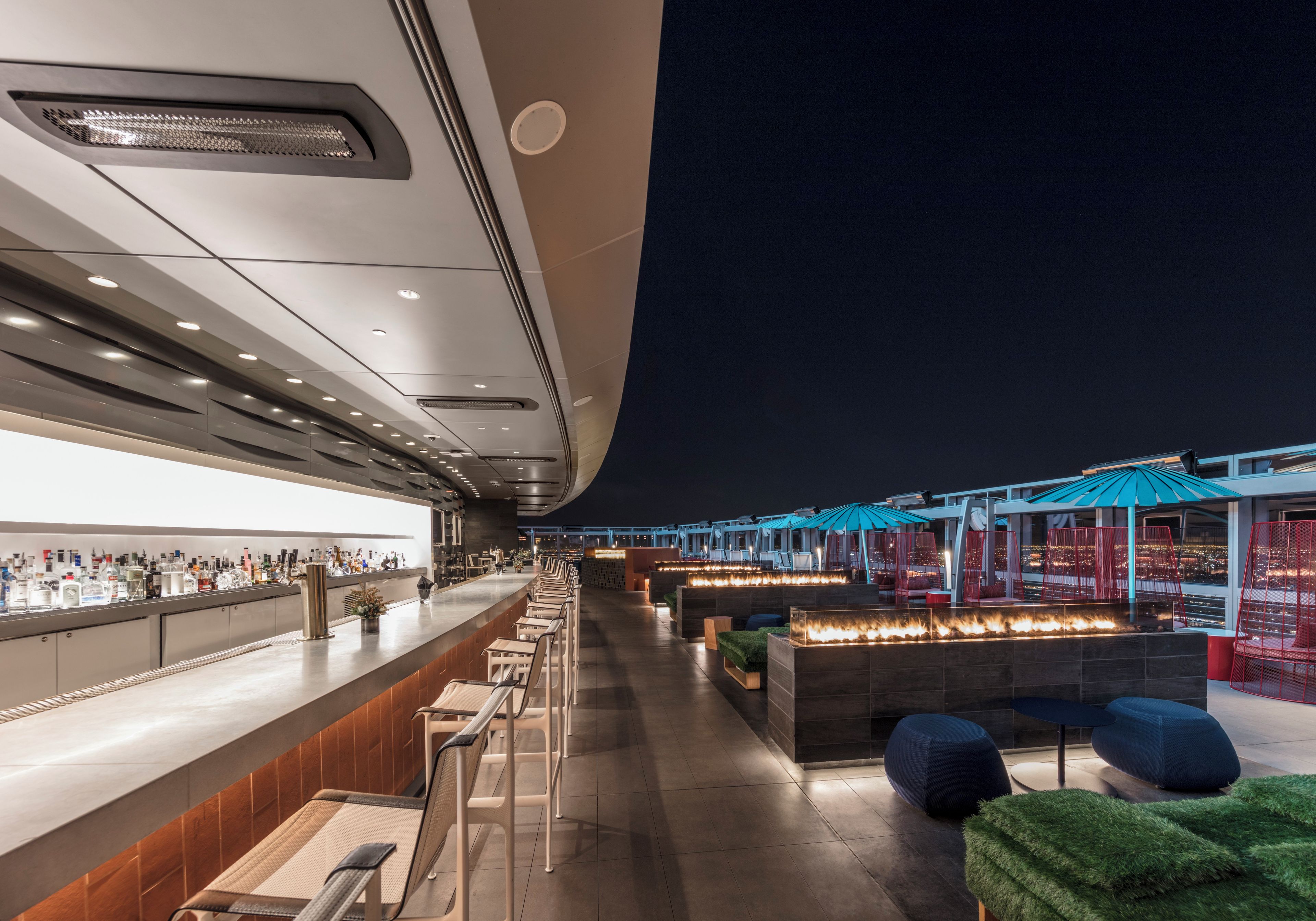 A bar area with seating and a view of the cityscape at night.
