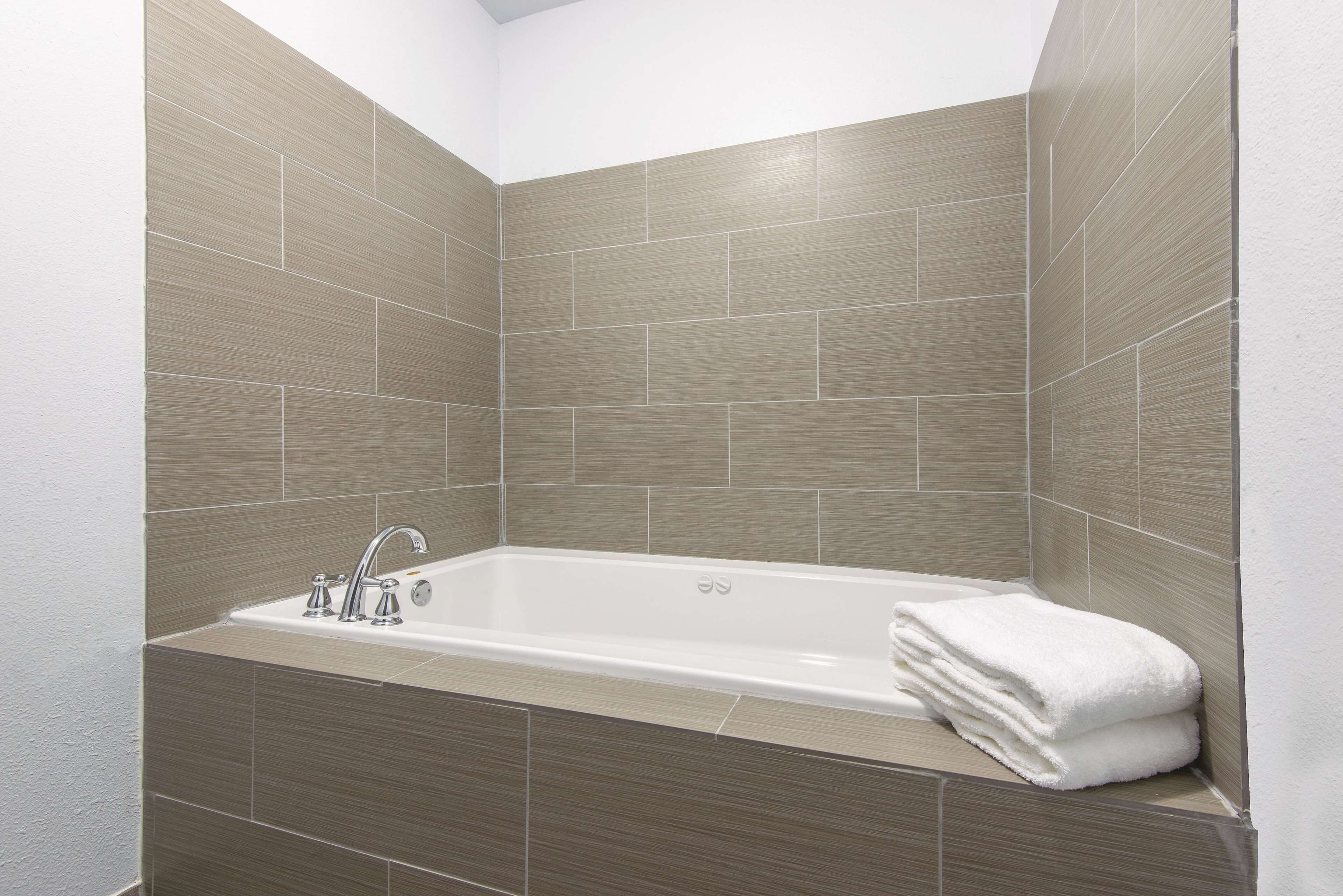 Een moderne badkamer met een vrijstaand bad, een wastafel met een kraan en een stapel witte handdoeken.