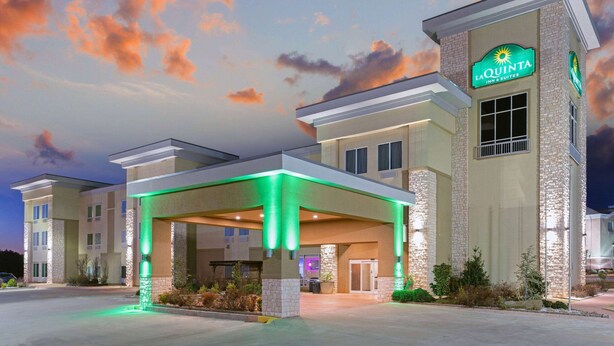 A hotel with a covered entrance, a sign reading "La Quinta Inn & Suites," and a brick facade.