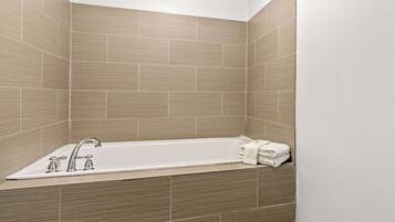 A corner bathroom with a freestanding bathtub, a single faucet, and a towel rack.