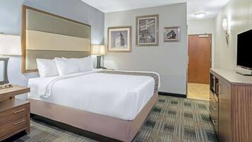 A hotel room with a large bed, bedside tables, a desk, a television, and framed pictures on the wall.