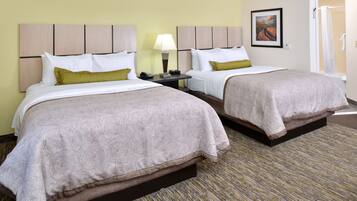 A hotel room with two beds, a nightstand with a lamp, a painting on the wall, and a shower area.